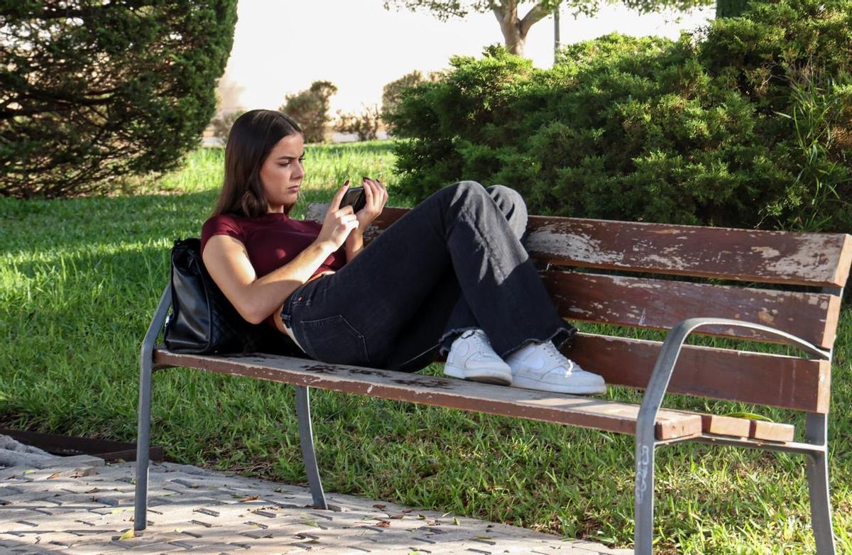 Una joven estudiante de Trabajo Social en la UA usa su móvil antes de entrar a clase