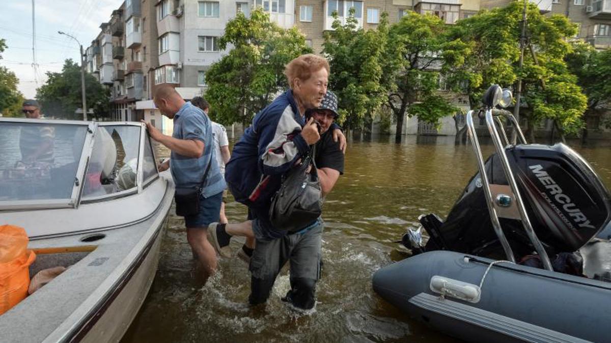 Los voluntarios entregan alimentos a los residentes locales en un área inundada, en medio del ataque de Rusia a Ucrania, en Kherson