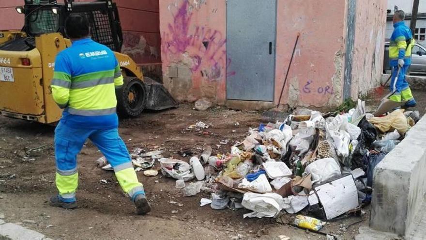 Dos trabajadores de Emaya recogen la basura de uno de los espacios entre bloques.