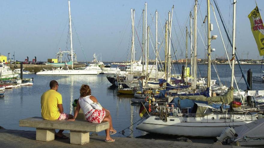 Dos personas en el muelle de Corralejo observan las embarcaciones atracadas.