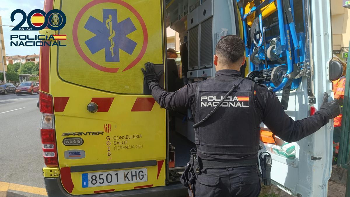 Un agente de Policía, junto a una ambulancia.