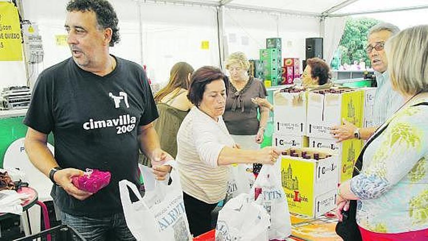 Miembros de la comisión de festejos reparten las botellas de vino y el bollu.