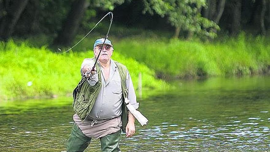 Un pescador lanza la caña en un río asturiano.