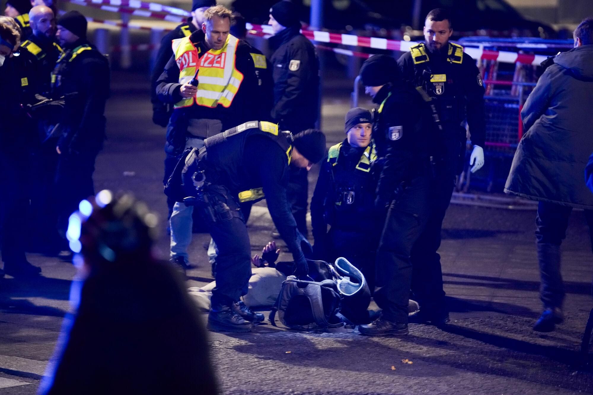 Police officers detain a man at the Holocaust memorial in Berlin, Germany, after another man was seriously injured, Friday, Feb. 21, 2025. (AP Photo/Ebrahim Noroozi)