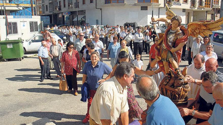 Arriba, los costaleros, con una imagen de San Miguel, cuya fiesta se celebra en plena vendimia. A la izquierda, los vecinos tras la misa