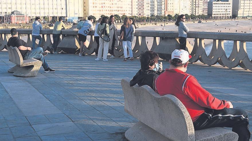 Dos personas sentadas en un banco del paseo marítimo durante la fase de desconfinamiento.