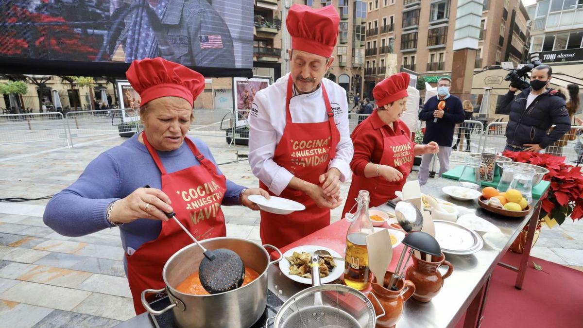 Maruja Moreno (i), Juan Antonio Marín y Victoria López cocinando en la plaza del Romea | JUAN CARLOS CAVAL