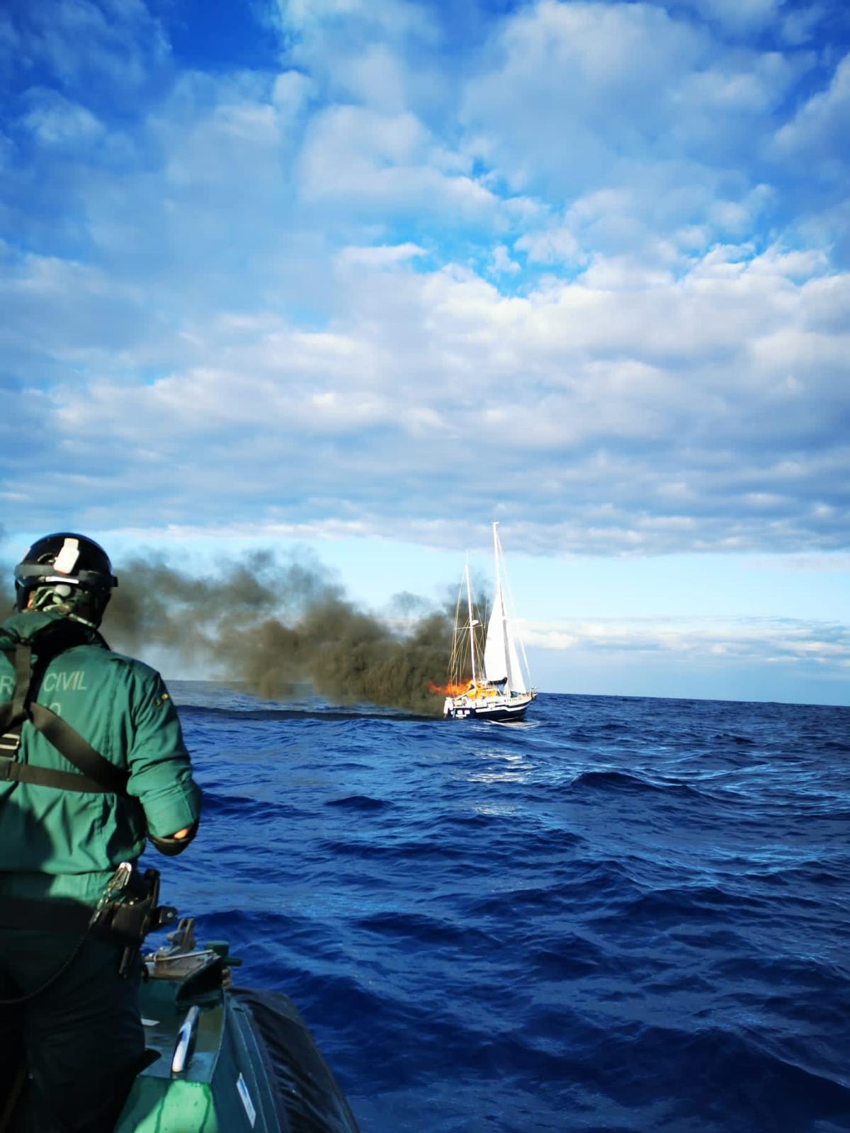 Un agente de la Guardia Civil observa el velero Magallanes tras el incendio, en aguas próximas a Canarias.
