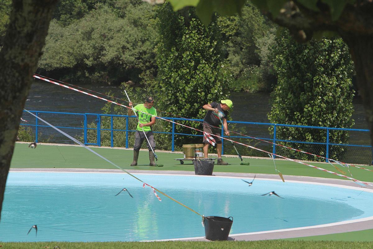 Dos personas se refrescan con el agua de una fuente en el parque de Oira.