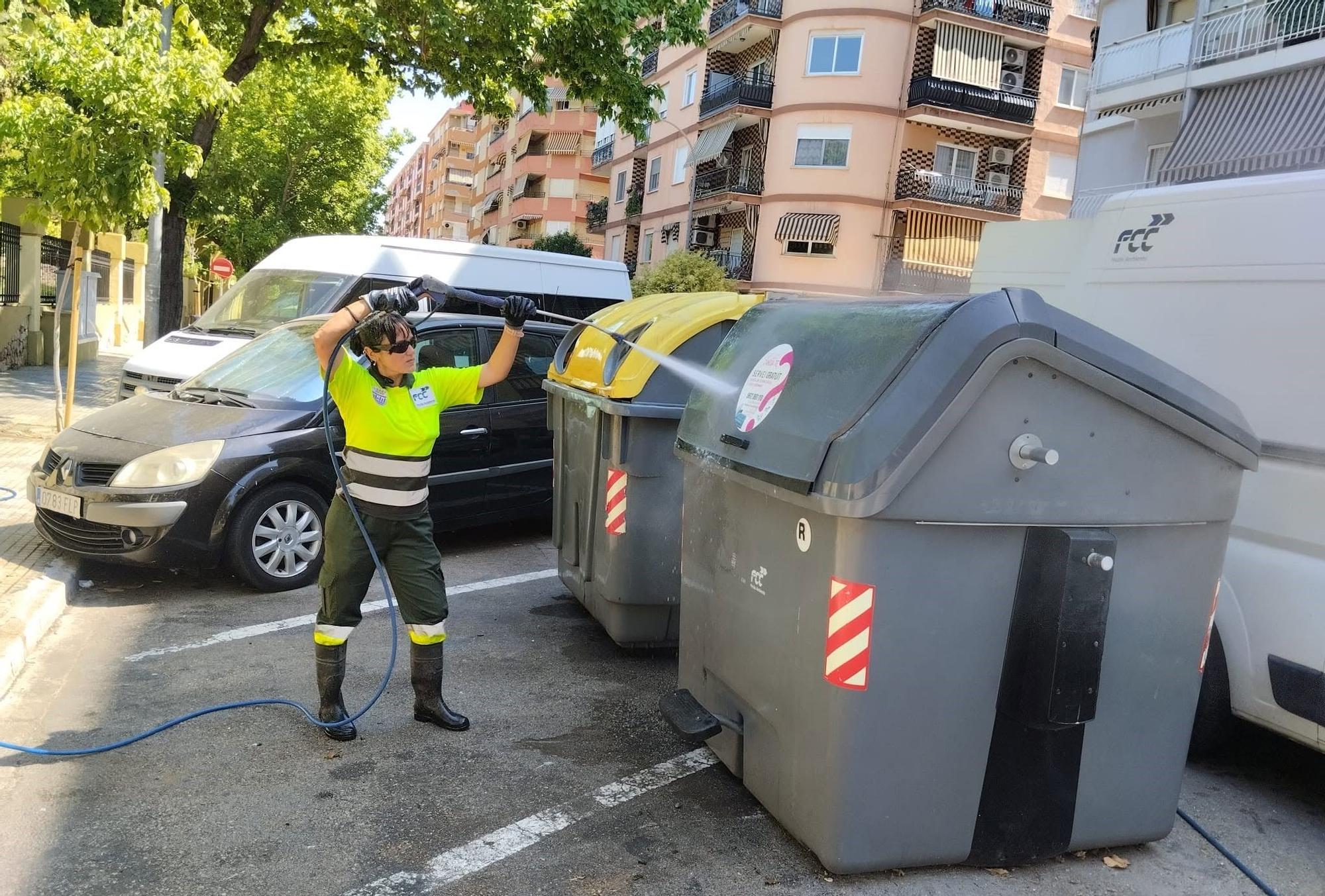 Una trabajadora de FCC en Gandia limpia unos contenedores.