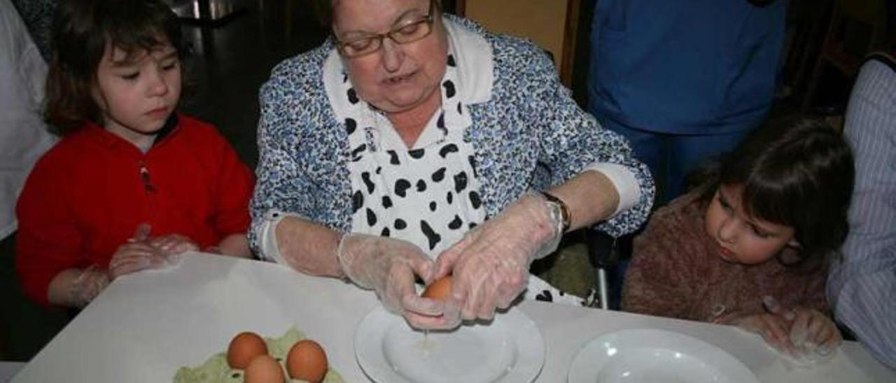 Pilar Lago enseña a las pequeñas Claudia Mera y Cova García a separar la clara del huevo para hacer rosquillas.