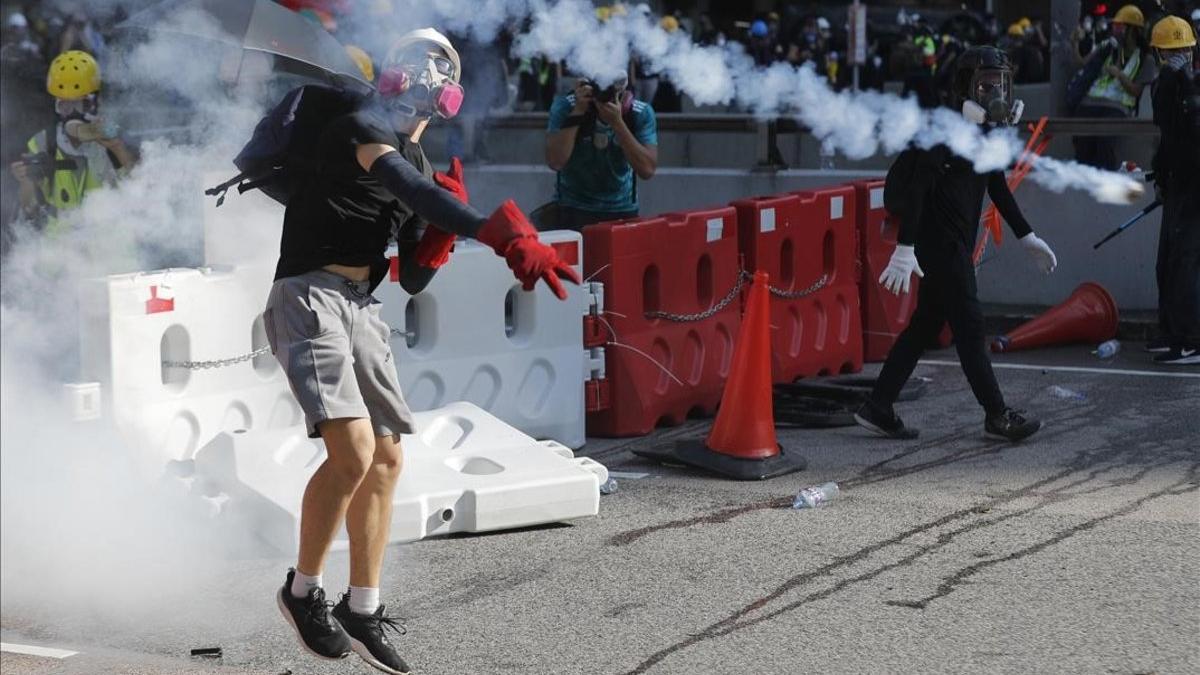 Un manifestante lanza un bote de gas lacrimógeno durante las protestas con motivo de la huelga general en Hong Kong.