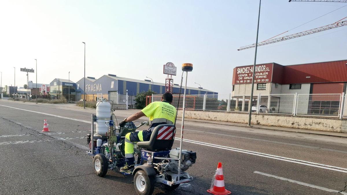 Un operario municipal repintando líneas en carretera de Badajoz.