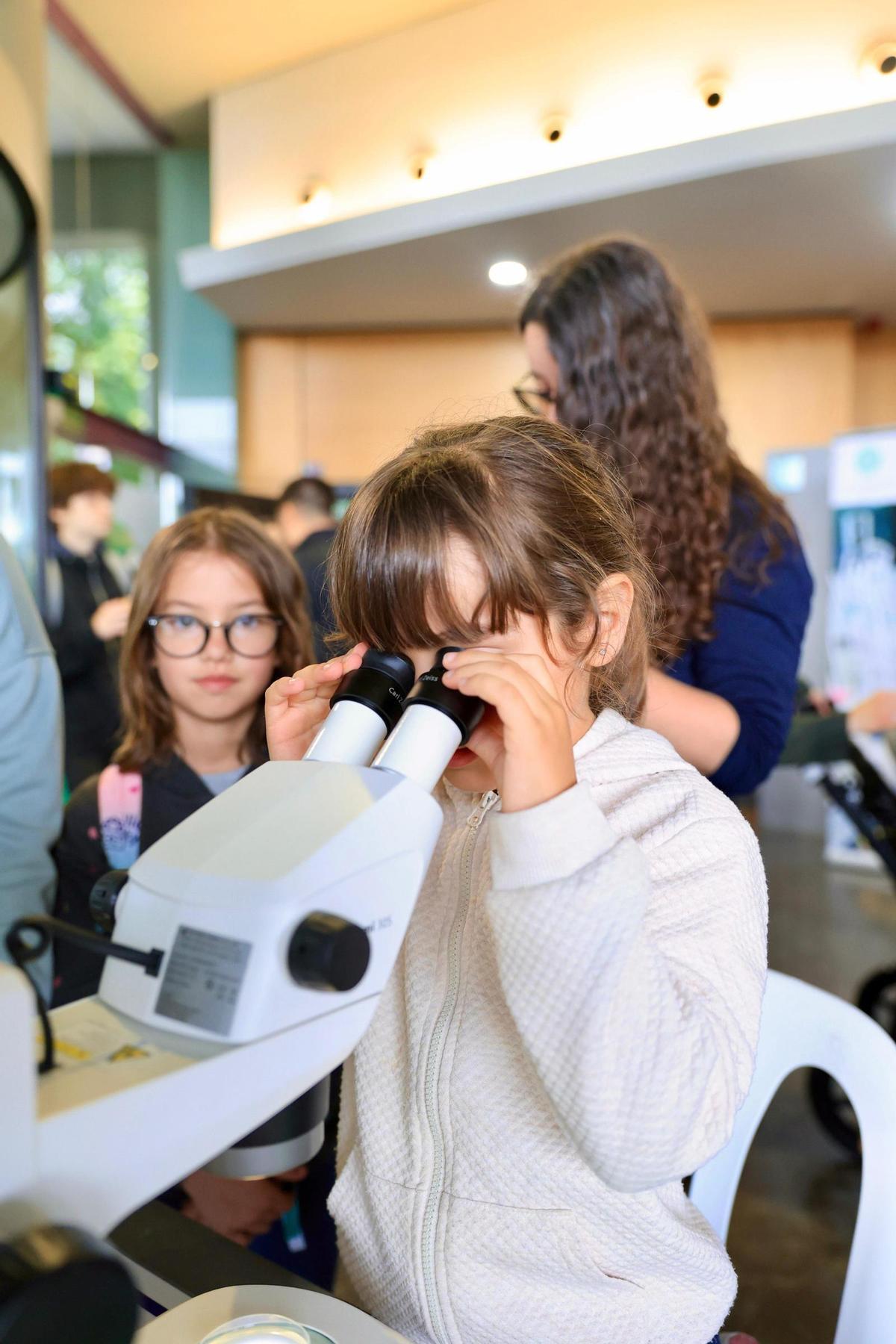 Una xiqueta descobrint el món microscòpic a Expociència.