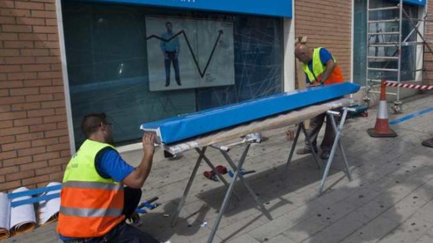 Los operarios colocan una cartel con la marca SabadellCAM.