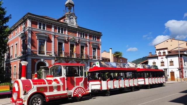 El tren turístico de Aller pasando por delante del Ayuntamiento de Cabañaquinta.