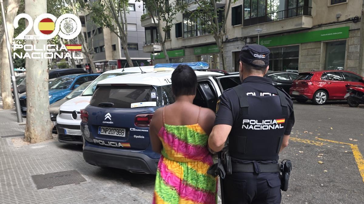 Un agente de la Policía Nacional lleva detenida a una de las presuntas estafadoras del anciano al que cuidaban.e su domicilio de Palma.