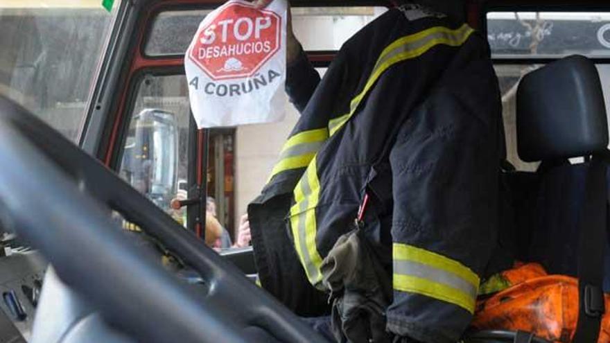 Un bombero, con una pancarta de Stop Desahucios. / Víctor Echave