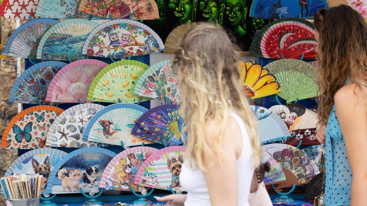 Dos jóvenes miran abanicos en el mercadillo de Sant Joan.