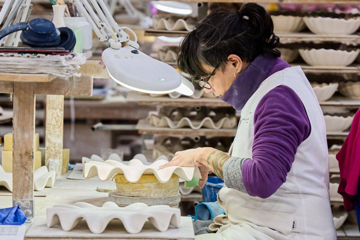 Treballadora corregint manualment les imperfeccions d'una de les peces de porcellana.