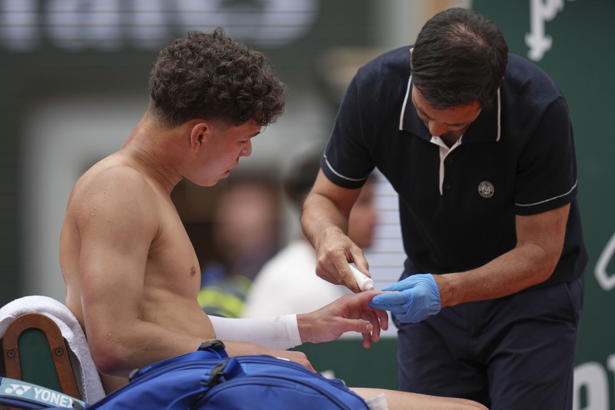 Ben Shelton of the U.S. gets medical assistance as he plays Spain's Carlos Alcaraz during their fourth round match of the French Tennis Open, at the Roland-Garros stadium, in Paris, Sunday, June 1 2025. (AP Photo/Christophe Ena)
