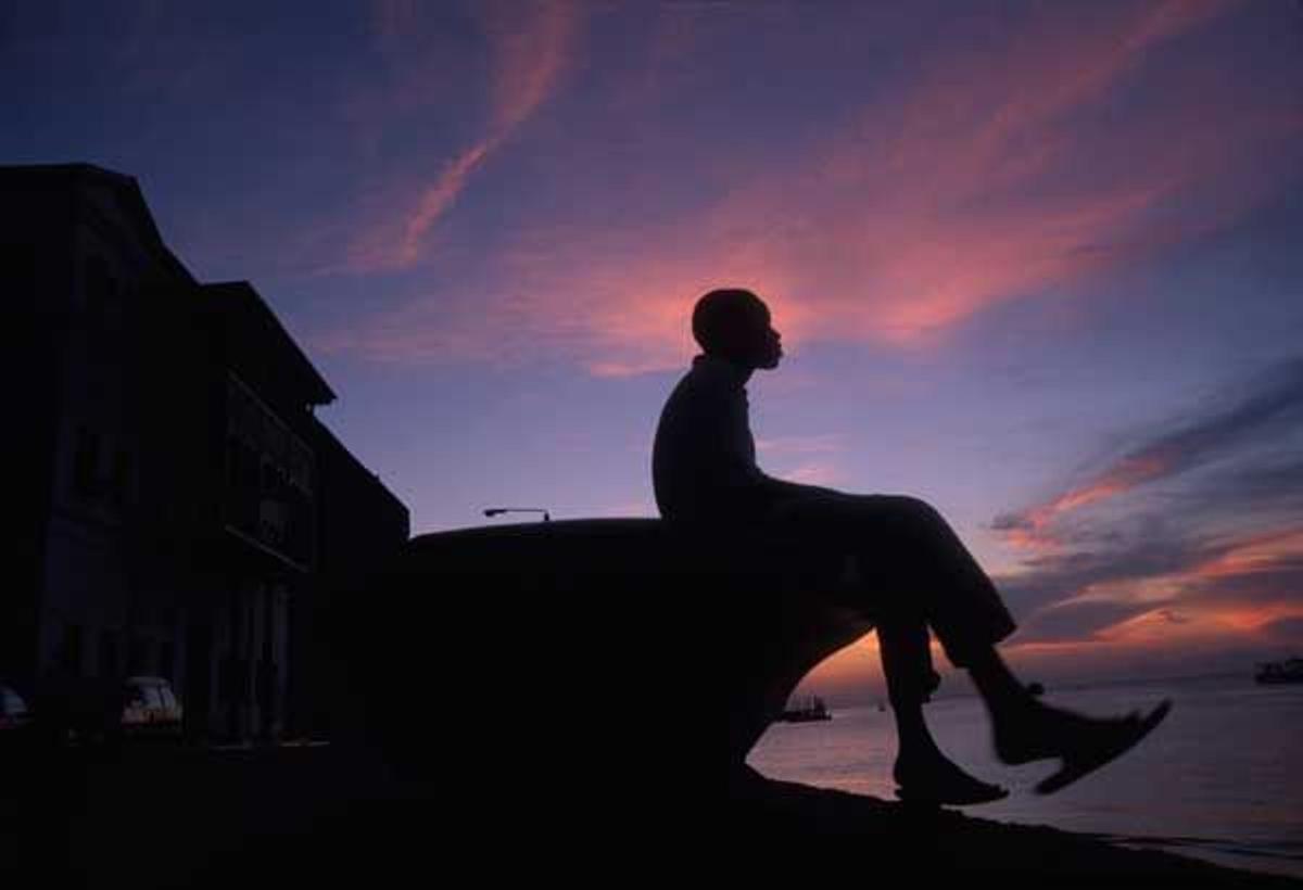 Silueta de un chico joven sentado en el puerto de Stone Town.