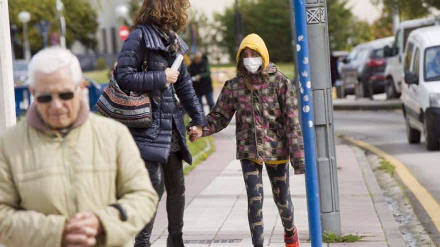 Una madre y su hija llevan mascarilla cerca de un hospital.