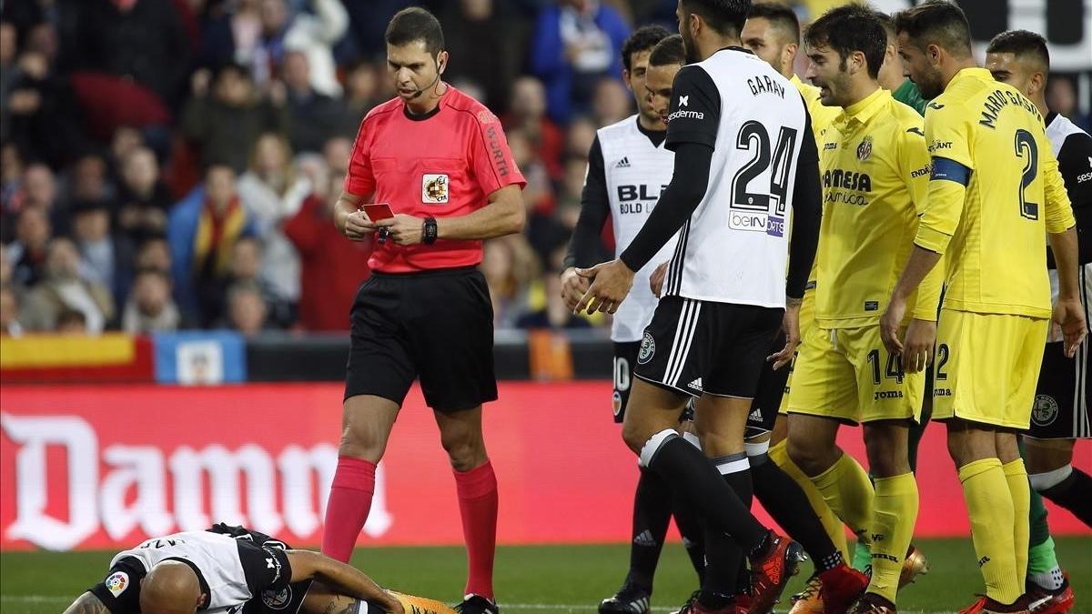 El árbitro del Valencia-Villarreal se dirige a mostrar la segunda amarilla a Zaza, en el suelo.