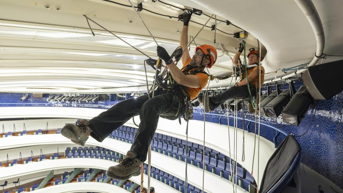 Dos alpinistas trabajan en una de las baldas del telón del Palau de les Arts para cambiar su iluminación.