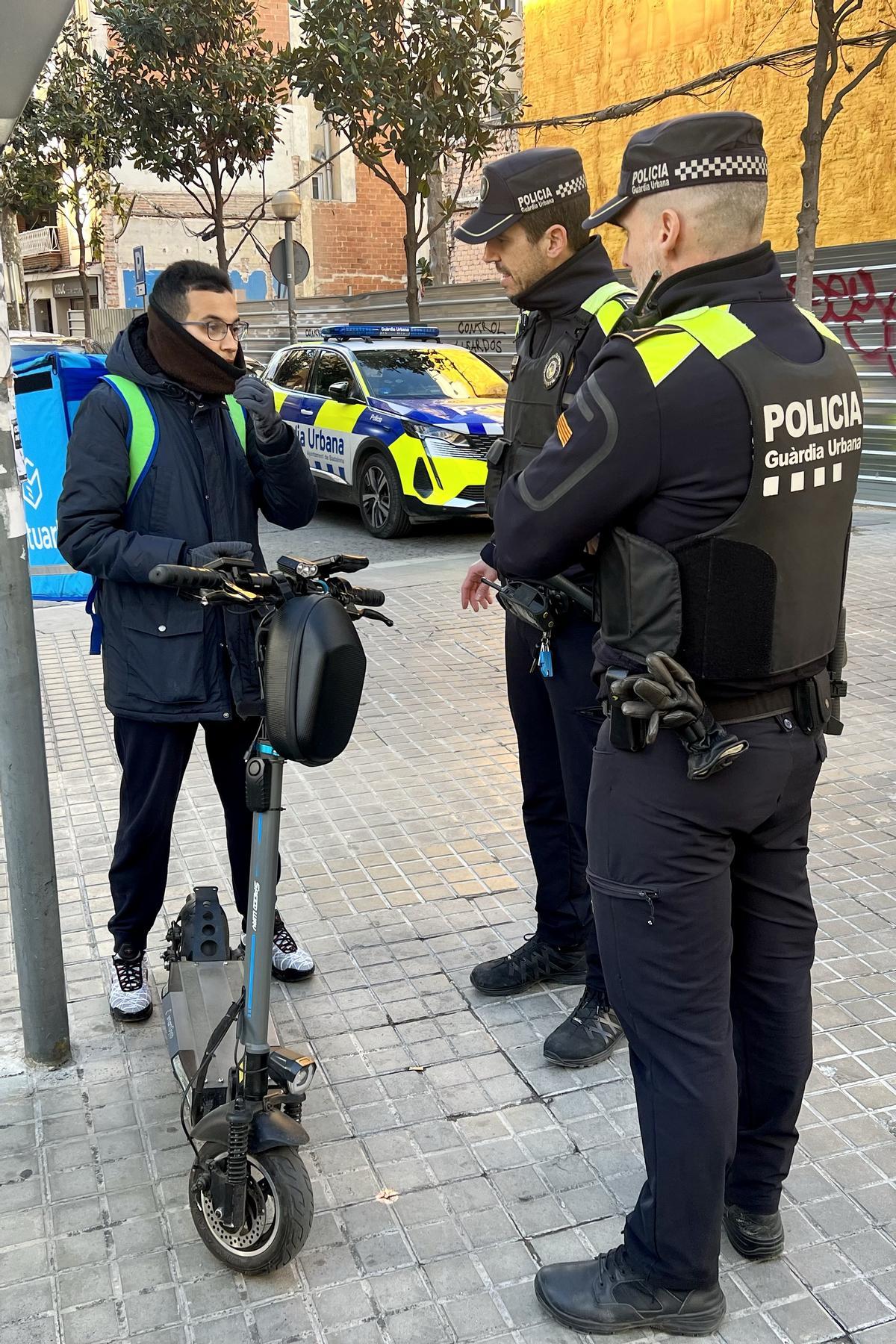 Agentes de la Guardia Urbana con el conductor de un patinete.