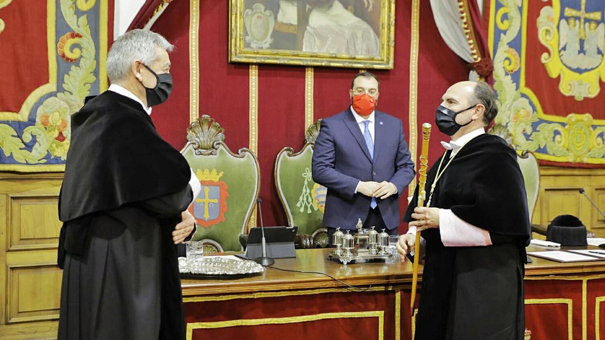 Ignacio Villaverde, ya convertido en rector, con el bastón de mando en la mano y la medalla de la Universidad colgada del cuello, mientras Santiago García Granda le muestra su cariño cruzando los brazos sobre su pecho. Al fondo, el presidente Adrián Barbón. | Universidad de Oviedo 