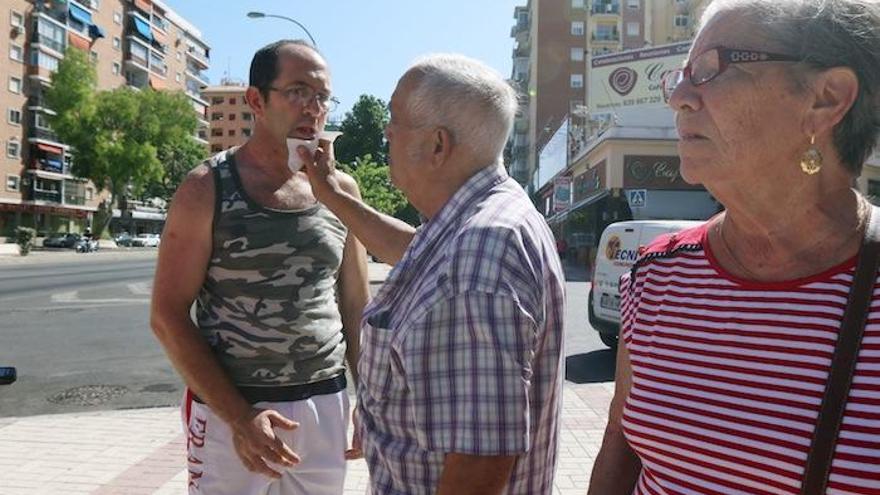 Juan Antonio Fernández, acompañado por sus padres, en la zona donde espera el autobús para el centro de día.