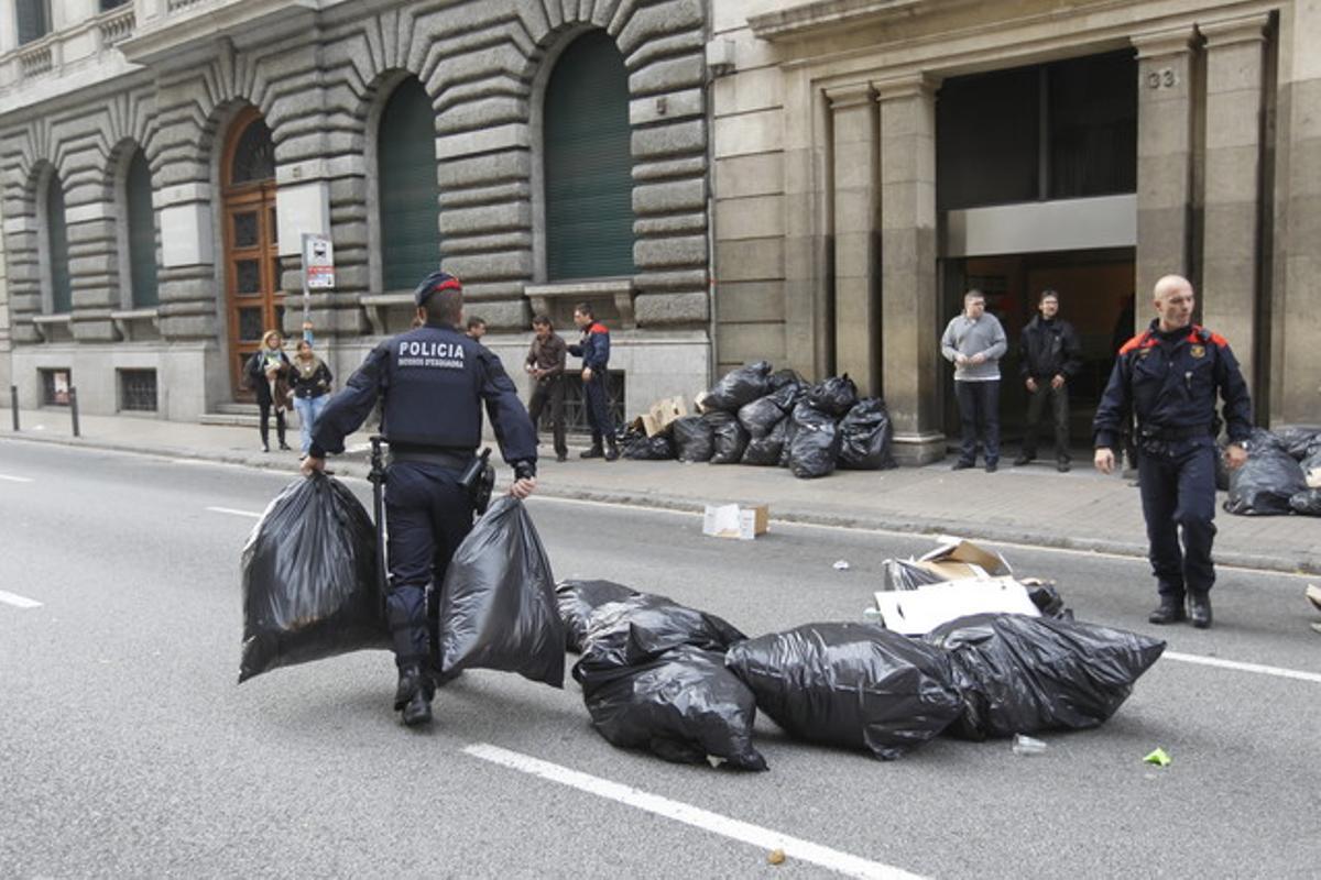 Unos mossos retiran bolsas de la Via Laietana tras un corte de tráfico.