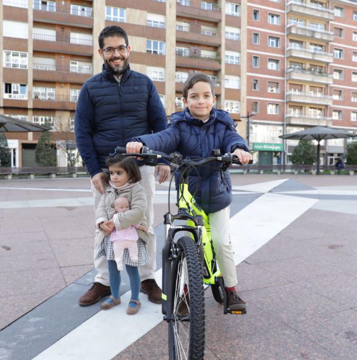 A la izquierda, Pablo Herrero estrenando bici junto a su padre, Ramiro Herrero, y su hermana Pilar en la plaza del Fresno; a la derecha, José Manuel Tejo y Sara Vázquez con sus hijos Rodrigo y Leonor en el Campo. | F. Rodríguez