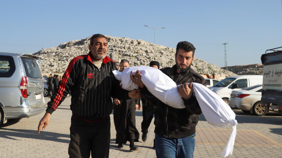 Unos hombres llevan el cuerpo de un niño sirio muerto en el terremoto.