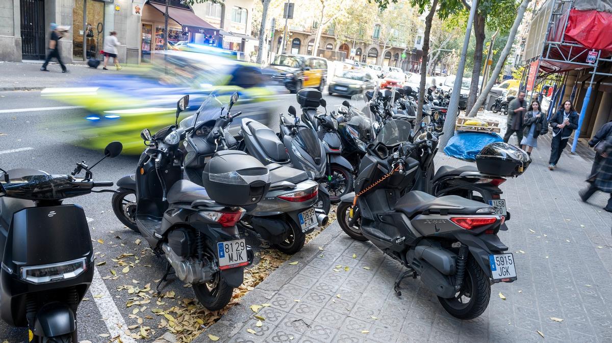 Un coche de la Guardia Urbana sube por la calle de Aribau, con motos en la acera a pesar del plan municipal.