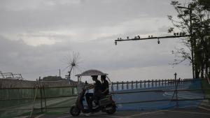Dos personas circulan en un ciclomotor eléctrico junto a una carretera cortada ante la llegada del tifón Saudel a Yuhuan, en la provincia de Zhejiang (China). 