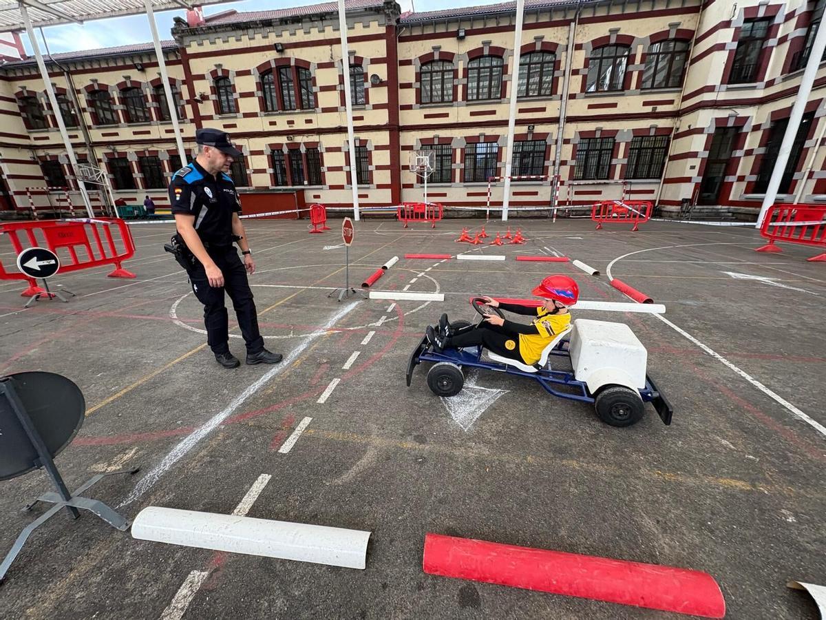 Miguel Pico conduce un kart en el patio del Liceo Mierense ante la mirada del policía Jesús Rodríguez.