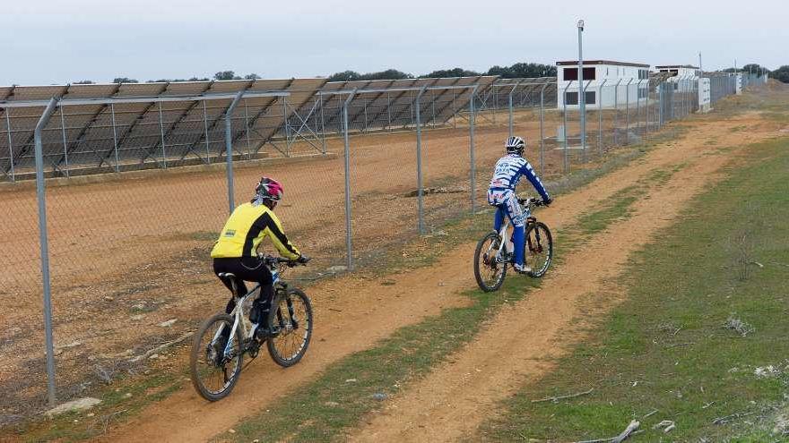 Dos ciclistas pasan frente a un parque fotovoltaico en Zamora.