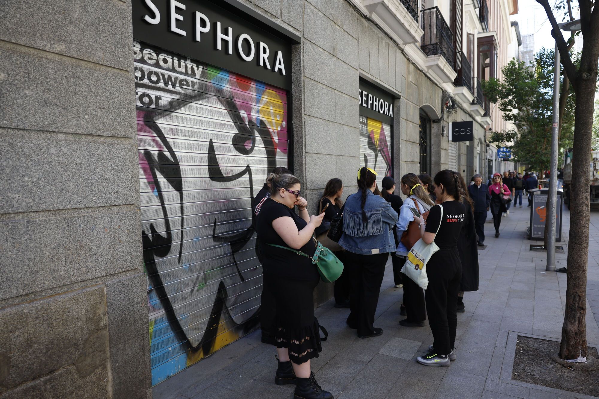 MADRID, 28/04/2025.- Trabajadoras de una tienda de cosméticos aguardan ante el cierre bajado del comercio durante el apagón, tras el corte de suministro eléctrico este lunes.