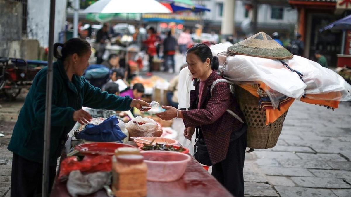 Una mujer compra en un mercado de Xiangxi, en la provincia de Hunan.