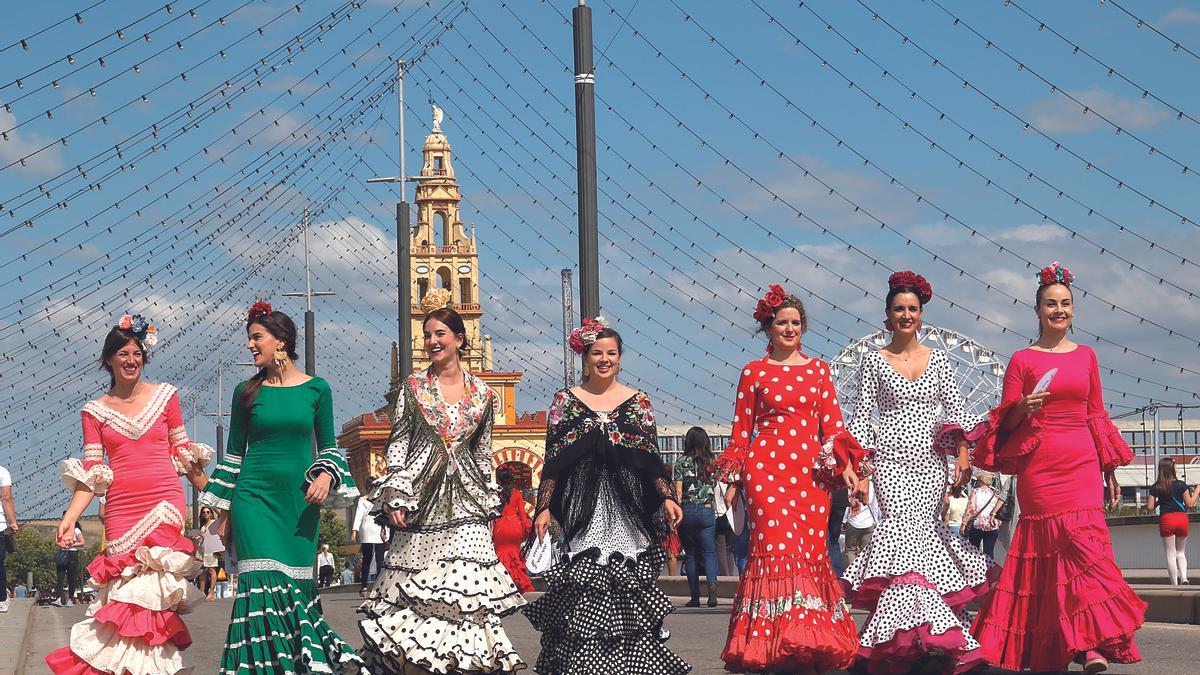 Pisando fuerte |  Un grupo de jóvenes, con trajes de flamenca, caminan desde el real de la Feria por el Puente de El Arenal.