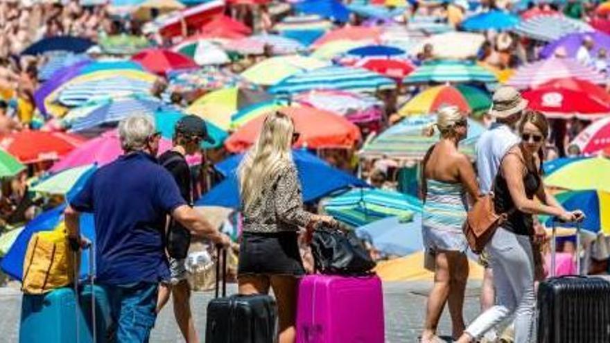 Turistas pasean con sus maletas en Benidorm en una jornada llena de visitantes.