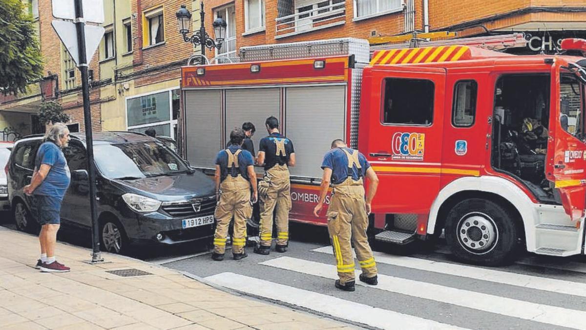 Los bomberos analizando los daños ocasionados a un coche aparcado, ayer. | LNE