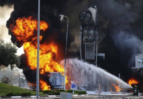 Bomberos extinguen un incendio que se desató después de que un misil palestino golpease un camión cisterna de combustible en una gasolinera en Israel.