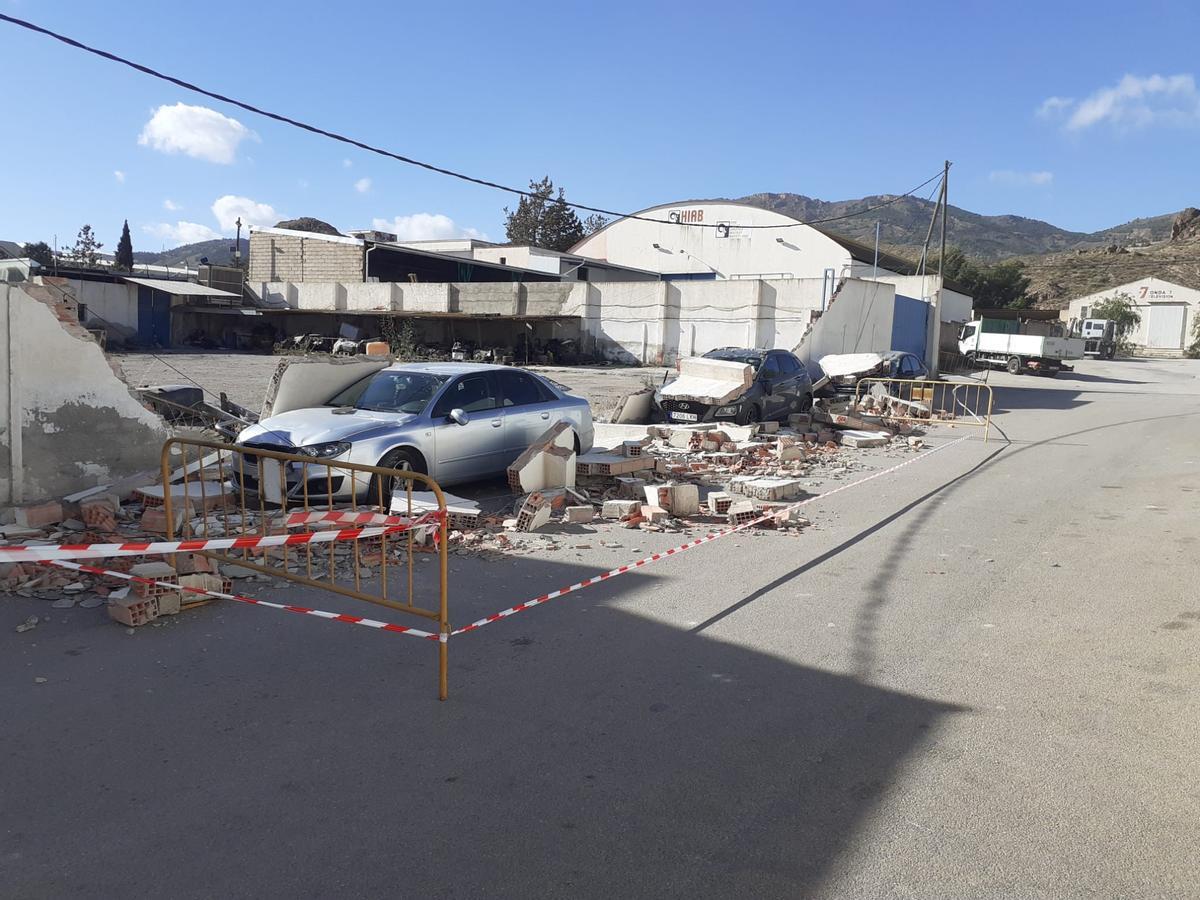 El muro de una parcela del Polígono de Los Peñones, en Lorca, caía sobre tres vehículos aparcados en la calzada, este martes.