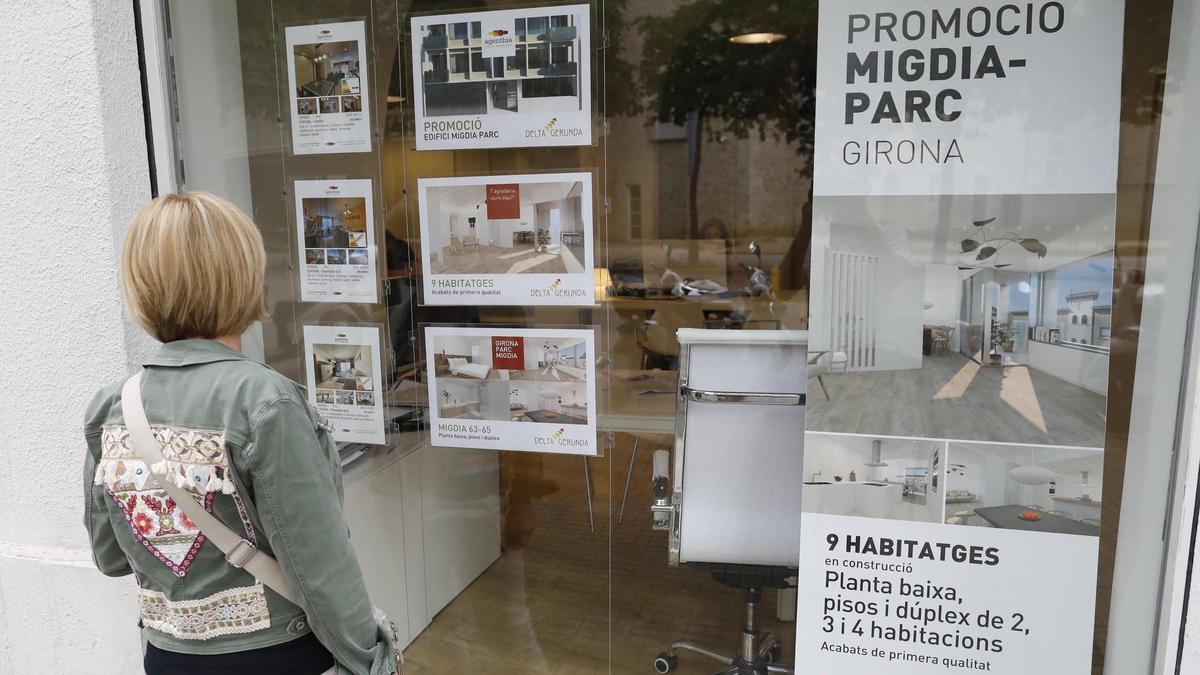 Una dona davant l’aparador d’una immobiliària a Girona, en una imatge d’arxiu.