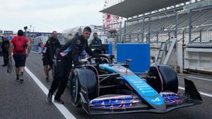 Los mecánicos de Alpine empujan el coche de Esteban Ocon en el pit lane de Suzuka