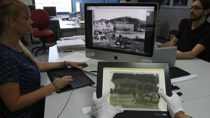 Virginia García, de la empresa RAW, muestra en la pantalla la imagen restaurada y en primer plano, el negativo original, con la emulsión desprendida. El negativo se preserva entre cristales y se conserva en el archivo, mientras que es la imagen digital la que se trabaja.