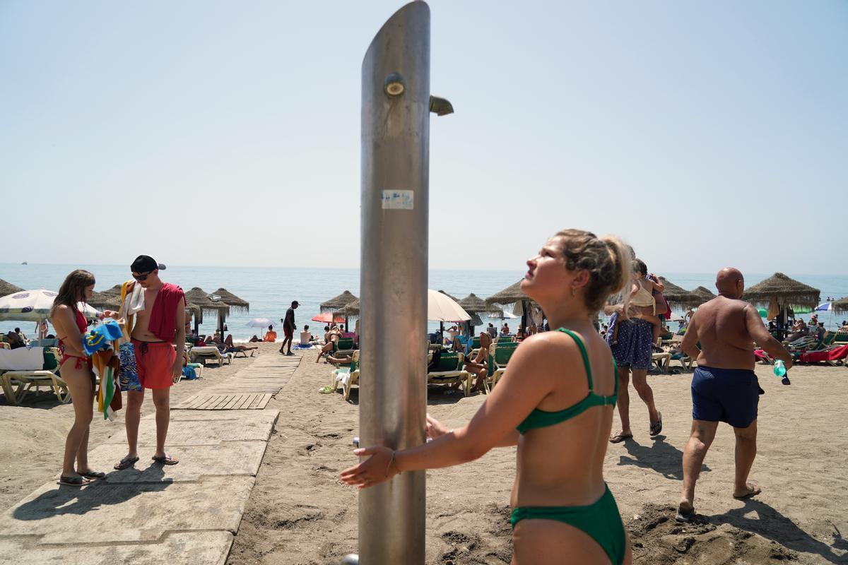 Usuarios de las playas de Málaga usan las duchas y lavapiés días antes de que corten en el agua. Agosto de 2023.